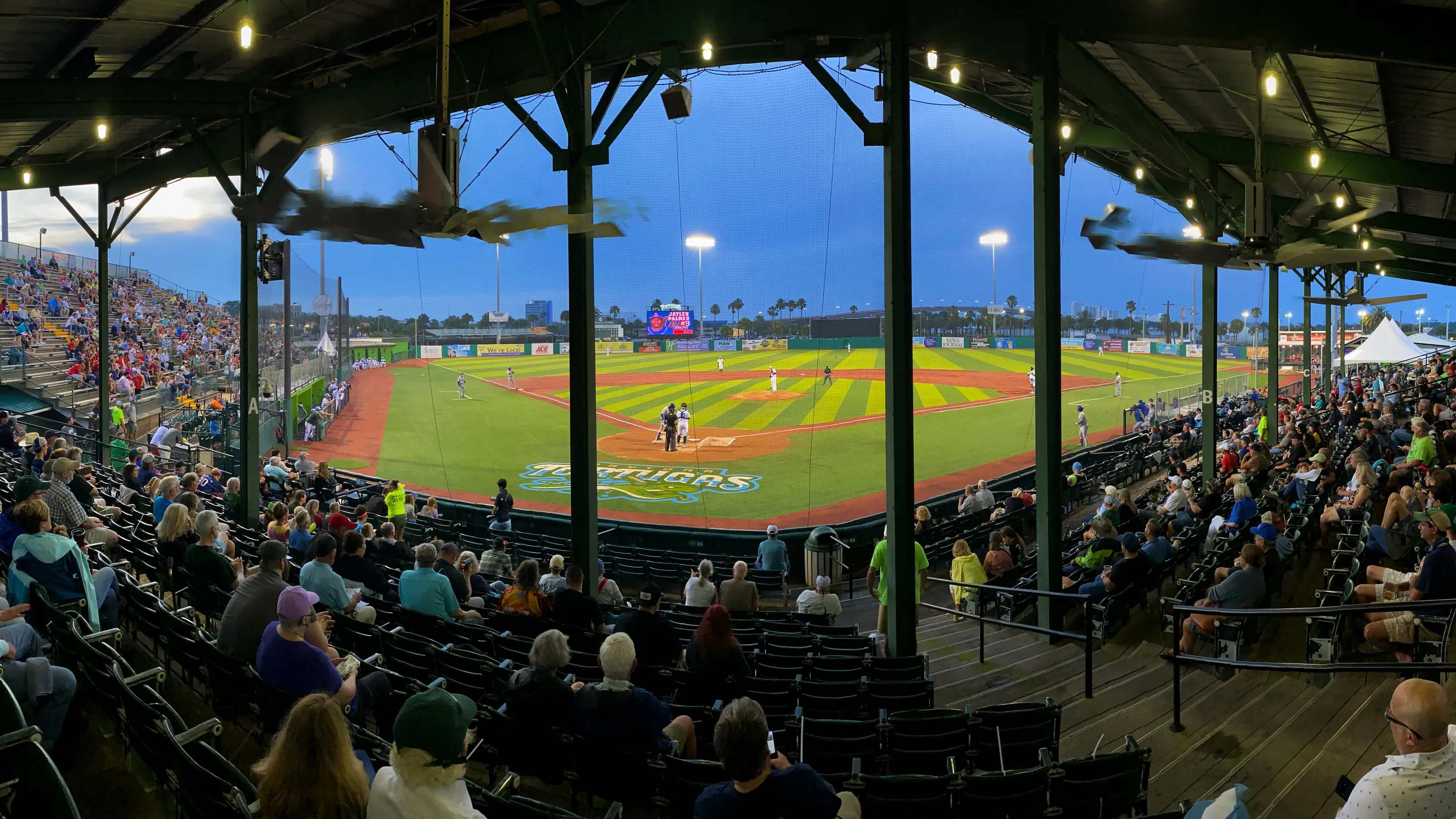 Crowd watching a baseball game at dusk from the grandstand at Jackie Robinson Ballpark in Daytona Beach